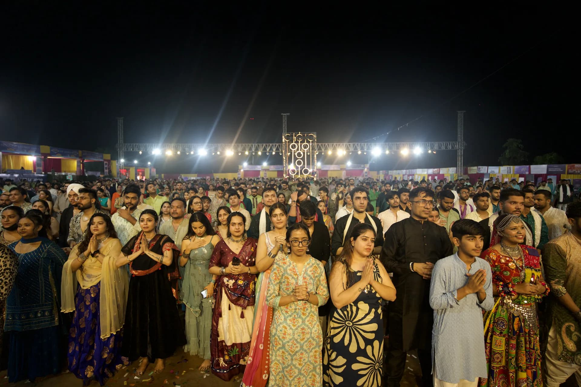 The crowd standing together with hands raised in prayer before the stage
